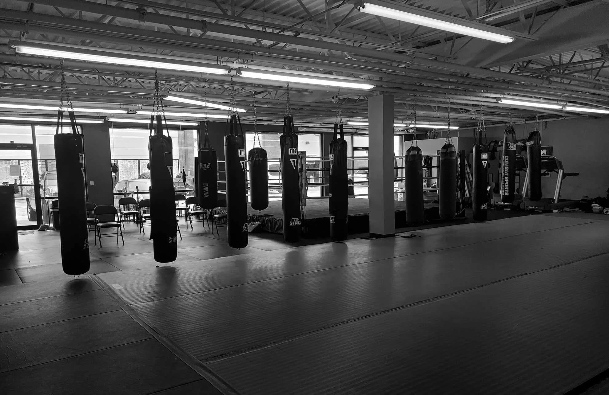 Salle d’entraînement ZK Training Camp équipée de sacs de frappe et d’un ring